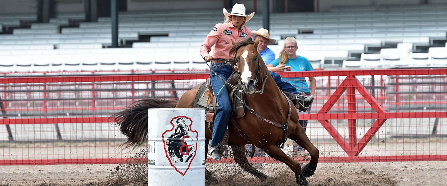 Women rides horse around barrel
